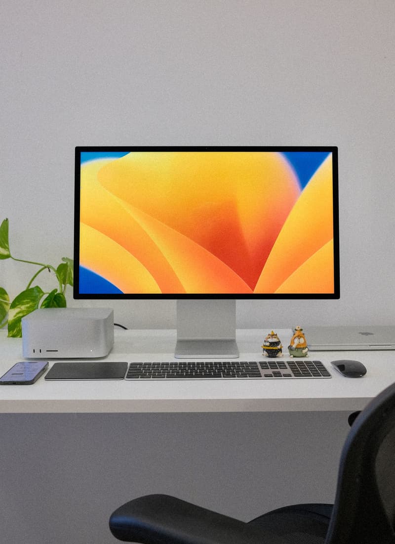 Postazione desktop moderna con monitor, tastiera e accessori su una scrivania minimale