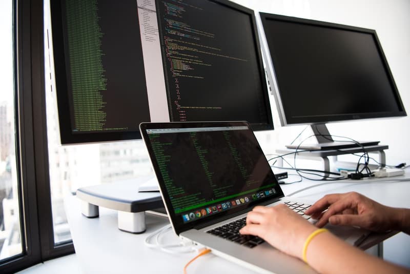 Sviluppatore al lavoro su più schermi con codice sorgente