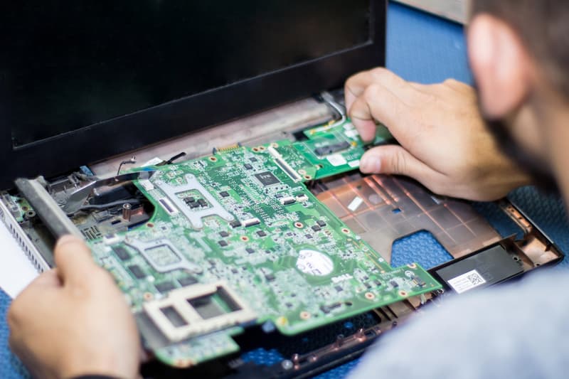 Fotografia di un tecnico che estrae la scheda madre da un computer portatile durante un intervento di riparazione