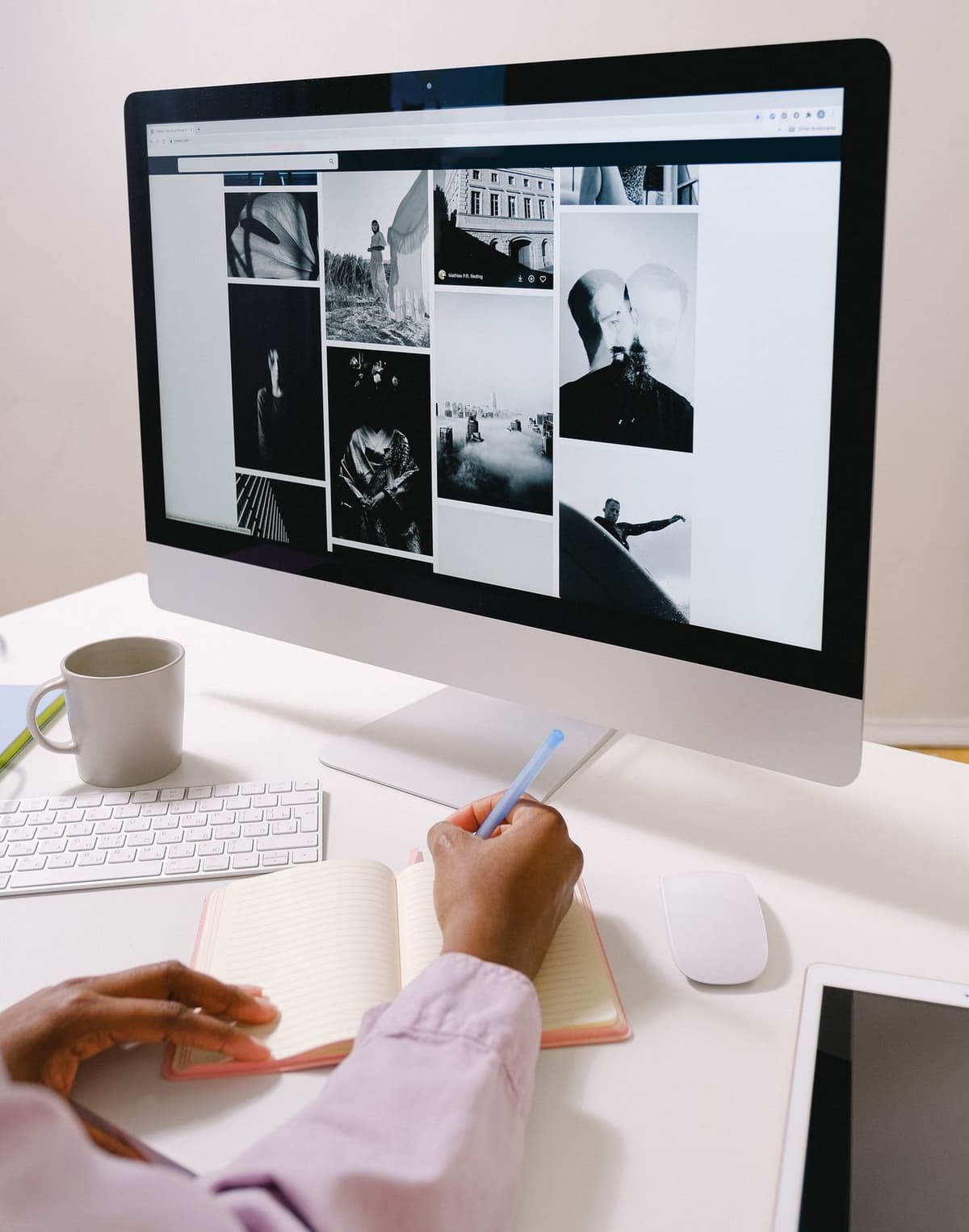Persona che scrive appunti a mano davanti a un monitor desktop